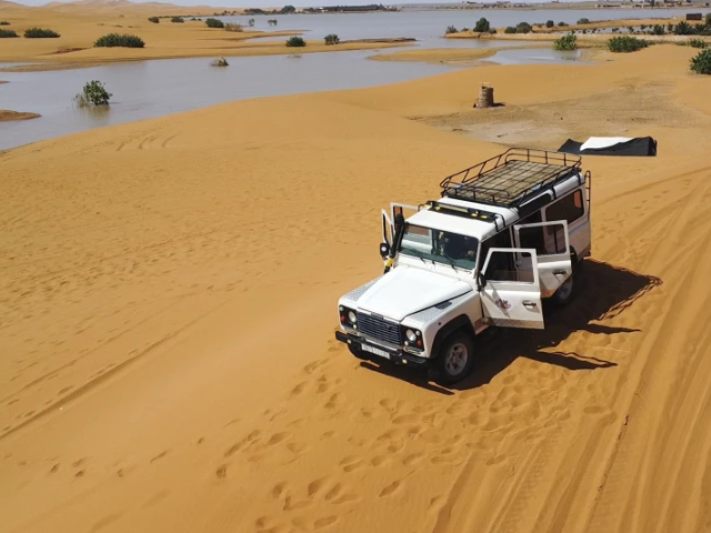 A vehicle transports tourists on sand dunes next to a lake caused by heavy rainfall in the desert town of Merzouga, near Rachidia, southeastern Morocco, Wednesday, Oct. 2, 2024. (AP Photo)